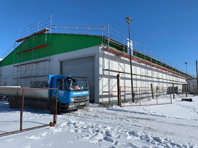 Eingerüstete Gewerbehalle mit Firmenfahrzeug von Gerüstbau Henze im Winter
