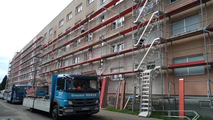 Firmenfahrzeug von Gerüstbau Henze vor einer eingerüsteten Baustelle